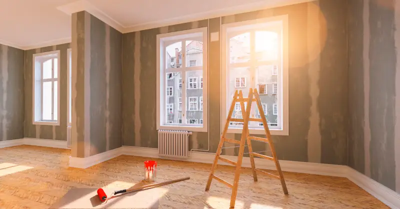 A ladder in the middle of a room with windows.