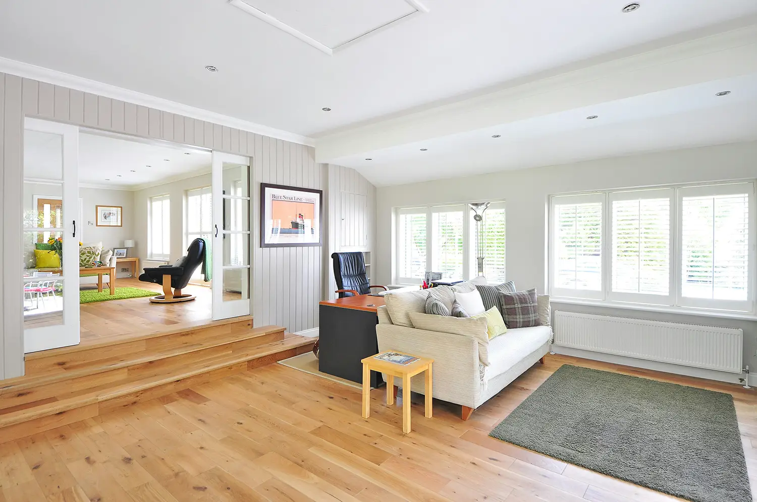 A living room with hard wood floors and white walls.