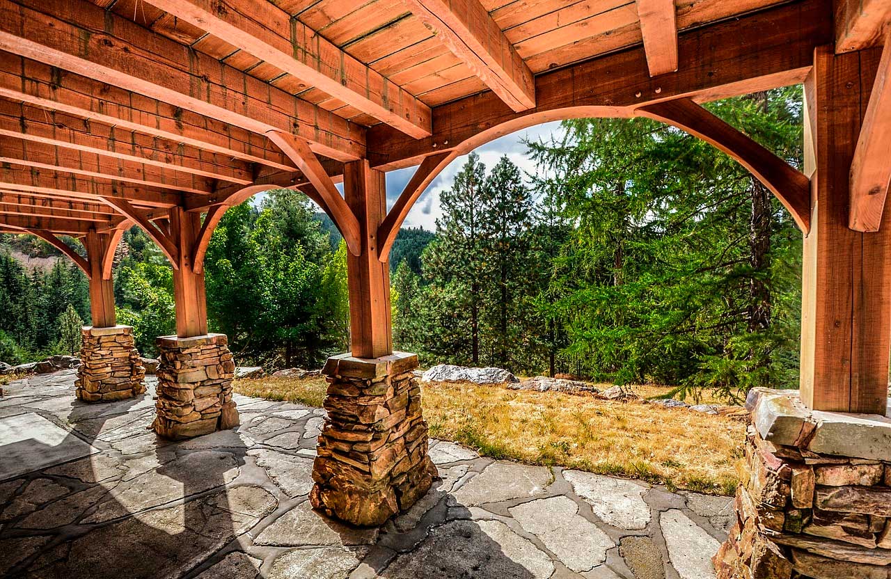 A wooden structure with stone pillars and a forest in the background.