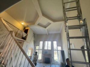 A ladder in the middle of a room with two people on it.