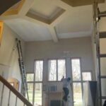 A man painting the ceiling of a house.